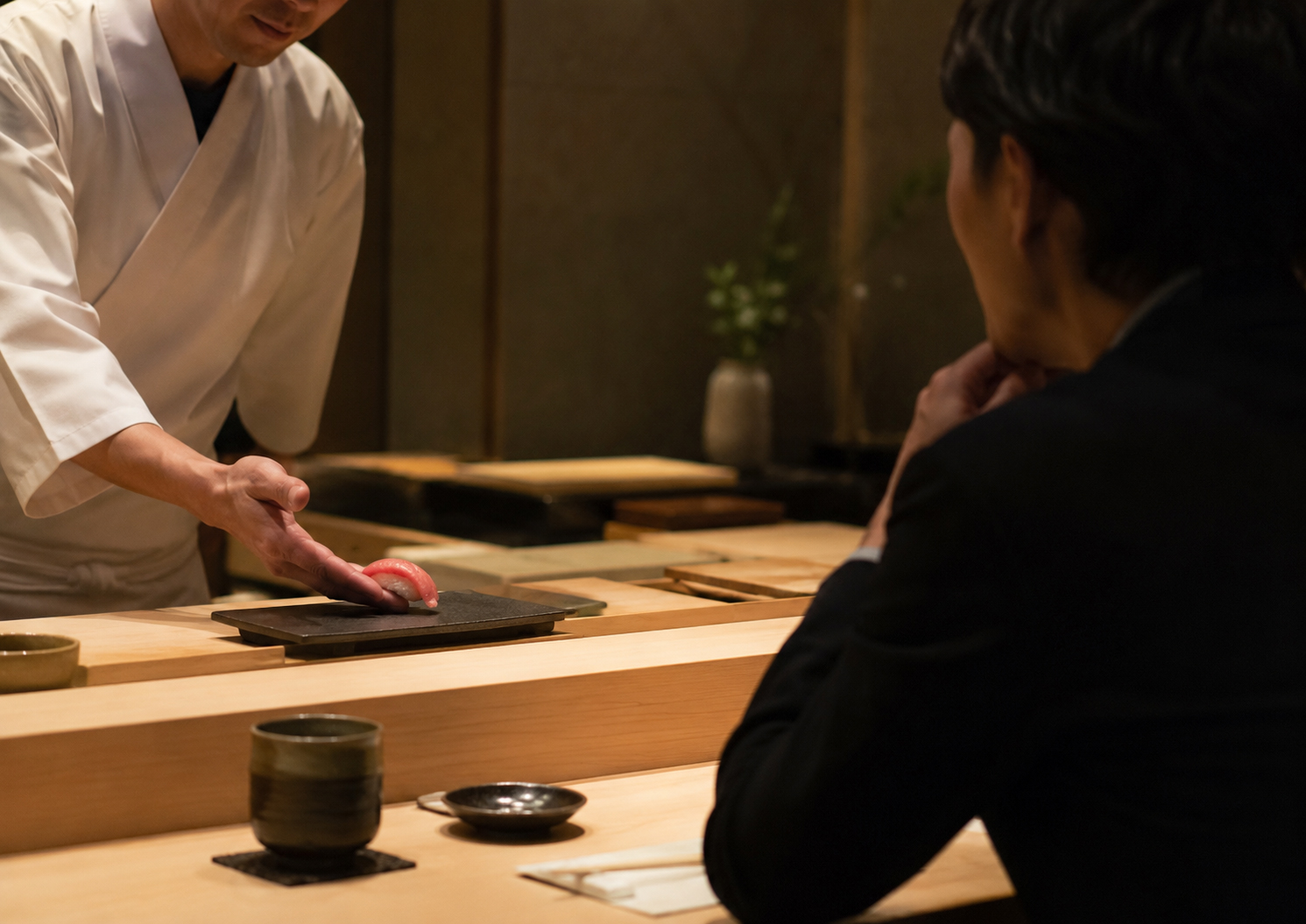 寿司カウンターで静かに会話しながらおまかせを味わう様子