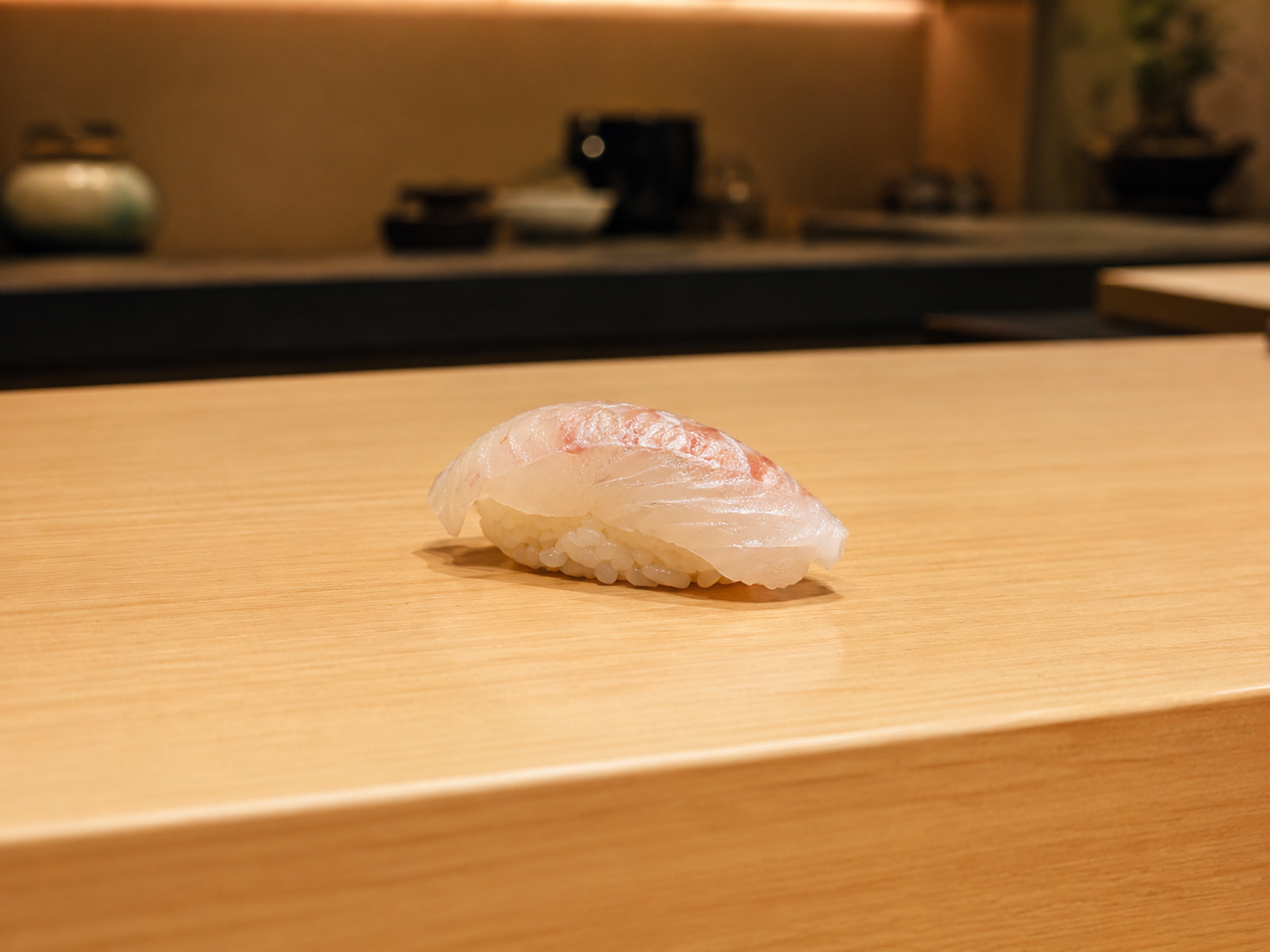 美しく仕上げられた白身魚の一貫がカウンターに置かれている